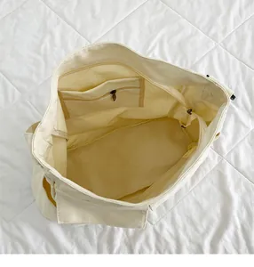 Interno della borsa tote in tela bianco avorio con ampio scomparto e tasche con zip