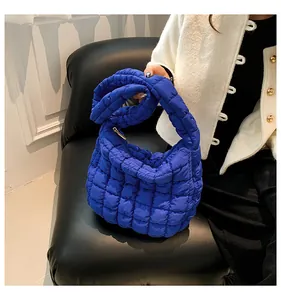 Detailopname van levendige koningsblauwe gewatteerde tas met glanzende nylon textuur en rits