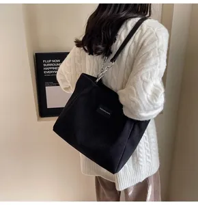Detalle del bolso tote de pana negra con correa de cadena plateada y etiqueta de moda