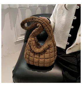 Detailweergave van karamel gewatteerde tas op lederen bank met winterse gebreide stijl
