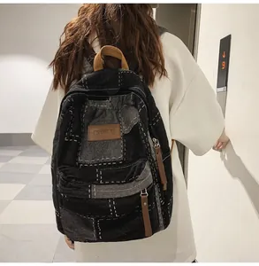 Dettaglio di uno zaino in denim patchwork vintage con cuciture bianche e cuoio