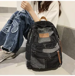 Dettaglio dello zaino in denim patchwork retrò con logo in pelle e tiranti marroni