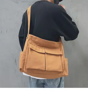 Dettaglio di una borsa a tracolla in tela giallo zenzero con ampie tasche frontali