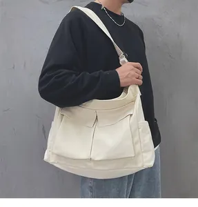 Dettaglio della borsa a tracolla beige in tela con due tasche frontali e tasche laterali