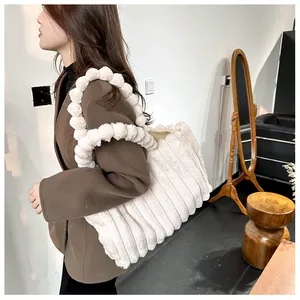 Gros plan du sac cabas en peluche beige avec bandoulière à pompons et texture côtelée