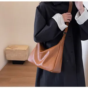 Detail van de karamelkleurige halve maan tas met brede riem gedragen door model