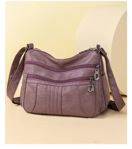 Detail of soft purple faux leather crossbody bag with multiple metal zipper compartments