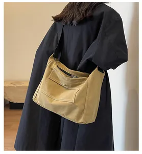 Detail of mustard yellow canvas crossbody bag with contrast stitching and metal snap pocket