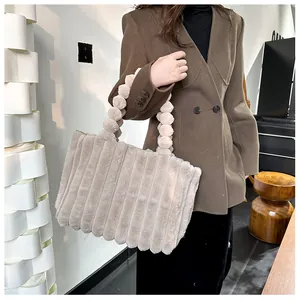 Détail du sac cabas en peluche beige avec texture rayée et anse à boules douces
