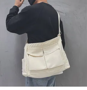Vista posteriore di una grande borsa a tracolla in tela bianca con design multi-tasca
