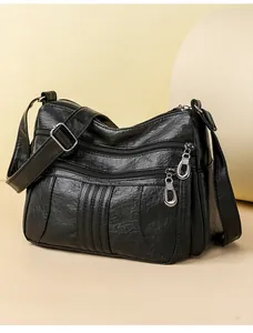 Detailed view of the black leather handbag featuring three functional metal zipper pockets