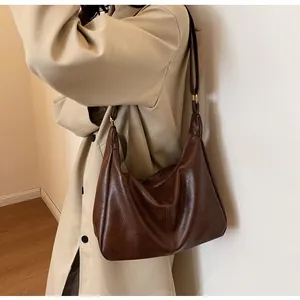 Detail van de donkerbruine PU-lederen hobo-tas met gouden ritssluiting en schouderriem