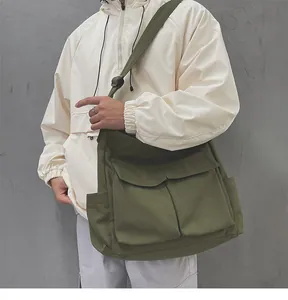 Dettaglio della borsa a tracolla in tela verde militare con ampie tasche frontali e design utility