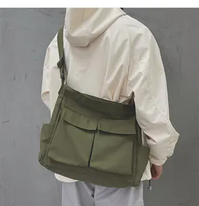 Dettaglio della borsa a tracolla in tela verde militare con grandi tasche e tracolla