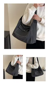 Detail of dark grey canvas messenger bag with white contrast stitching and front pocket