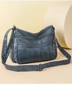 Close-up of deep blue soft leather shoulder bag with multiple zipper compartments and rings