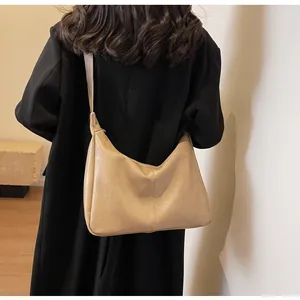 Detailopname van de kaki lederen hobo-tas gedragen door een model in een winterjas