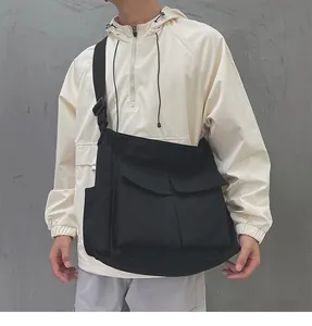 Dettaglio di una borsa a tracolla in tela nera con ampie tasche a patta e cinturino