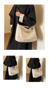 Detail showing high-capacity beige canvas messenger bag with black wide shoulder strap