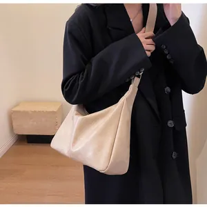 Detailweergave van de beige halvemaanvormige tas met zacht getextureerd leer en schouderband
