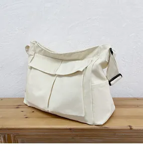 Dettaglio della borsa a tracolla in tela bianco crema con grandi tasche e tracolla