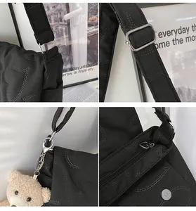 Detail van zwarte gewatteerde crossbodytas met hartritssluiting en een berenhanger