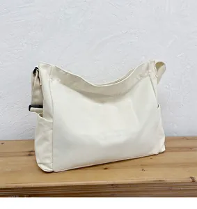 Dettaglio della borsa in tela beige con fibbia regolabile nera su superficie in legno