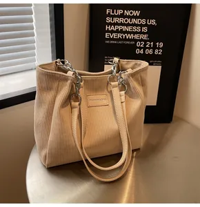 Detalle del bolso tote de pana beige con textura acanalada y correa de cadena plata
