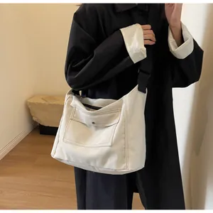 Detailed shot of white canvas messenger bag with metal snap pocket and black nylon strap