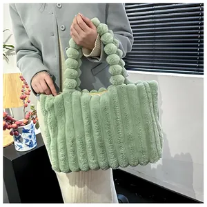 Détail du sac cabas peluche vert clair avec rayures et poignée boules en fourrure