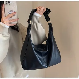 Detail van een zwarte mat PU-leren hobo-tas met brede riem en een gouden metalen gesp