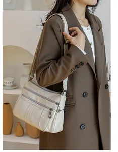 Detail of beige soft leather shoulder bag with multiple functional metal zippers