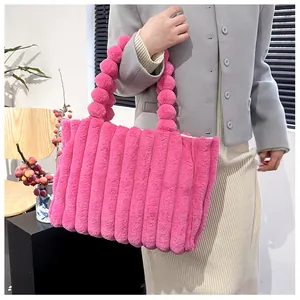 Gros plan du sac cabas en peluche rose avec rayures verticales et poignée en pompon