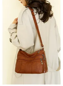 Detailed view of brown soft leather shoulder bag with multiple zip compartments on model