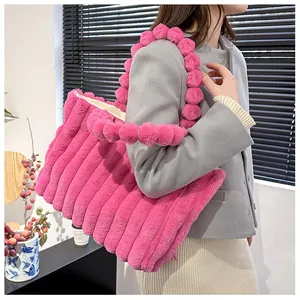 Sac fourre-tout fuchsia en peluche à rayures verticales et anse à pompons sur modèle