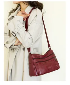 Close-up of wine red faux leather shoulder bag with multiple zippers and pebble texture