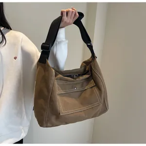 Detailed close-up of khaki canvas messenger bag with white stitching and silver snap button