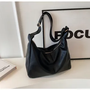 Detail van zwarte hobo tas met leertextuur, gouden ritssluiting en verstelbare schouderriem