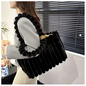 Détail d'un grand sac cabas en peluche noire avec rayures verticales et pompons doux