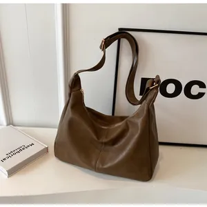 Detail van bruine PU-lederen hobo-tas met verticale stiksels en een gouden ritssluiting