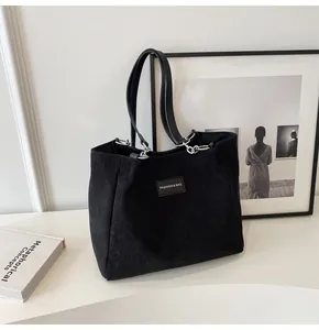 Detalle del bolso tote de pana negra con eslabones metálicos y textura de etiqueta