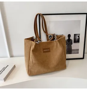 Detalle del bolso tote de pana con etiqueta de cuero y correa de cadena metálica