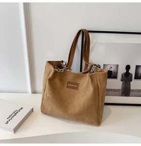 Detalle del bolso tote de pana retro con textura a rayas y correa de cadena de cuero
