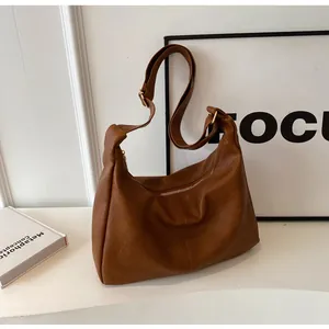 Detailweergave van bruine vintage PU-tas met zilveren rits en brede verstelbare riem