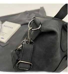 Nahaufnahme der grauen Metallbeschläge und der matten Wildlederstruktur der Handtasche
