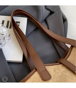 Detail eines glatten braunen Leder-Schultergurts an einer beigen Textil-Tragetasche