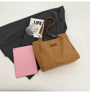 Primer plano de bolso tote de pana marrón con textura de rayas y etiqueta de cuero