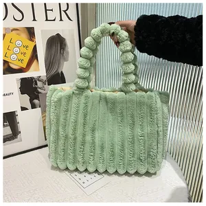 Détail du sac cabas en peluche vert clair avec texture côtelée et poignée à pompons