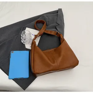 Detail van vintage karamelbruine hobo-tas met korrelige leertextuur en verstelbare riem