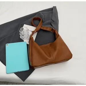 Bruine vintage hobo draagtas detail met verstelbare riem op een donkergrijze blazer
